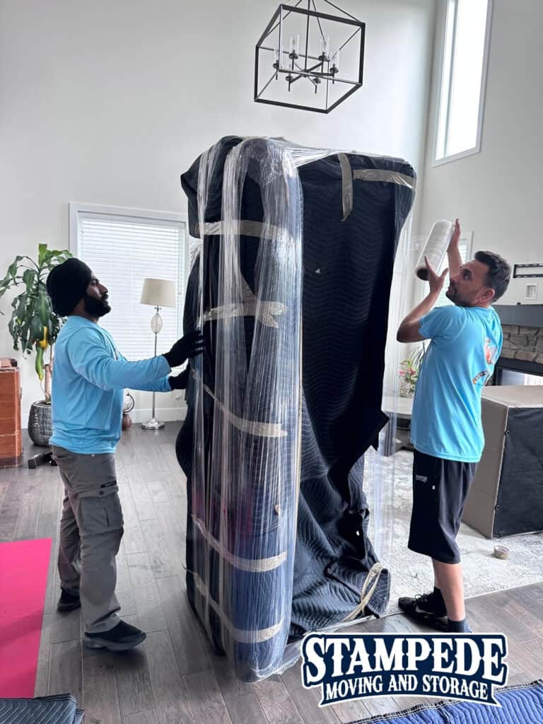 Movers wrapping large furniture in protective material.