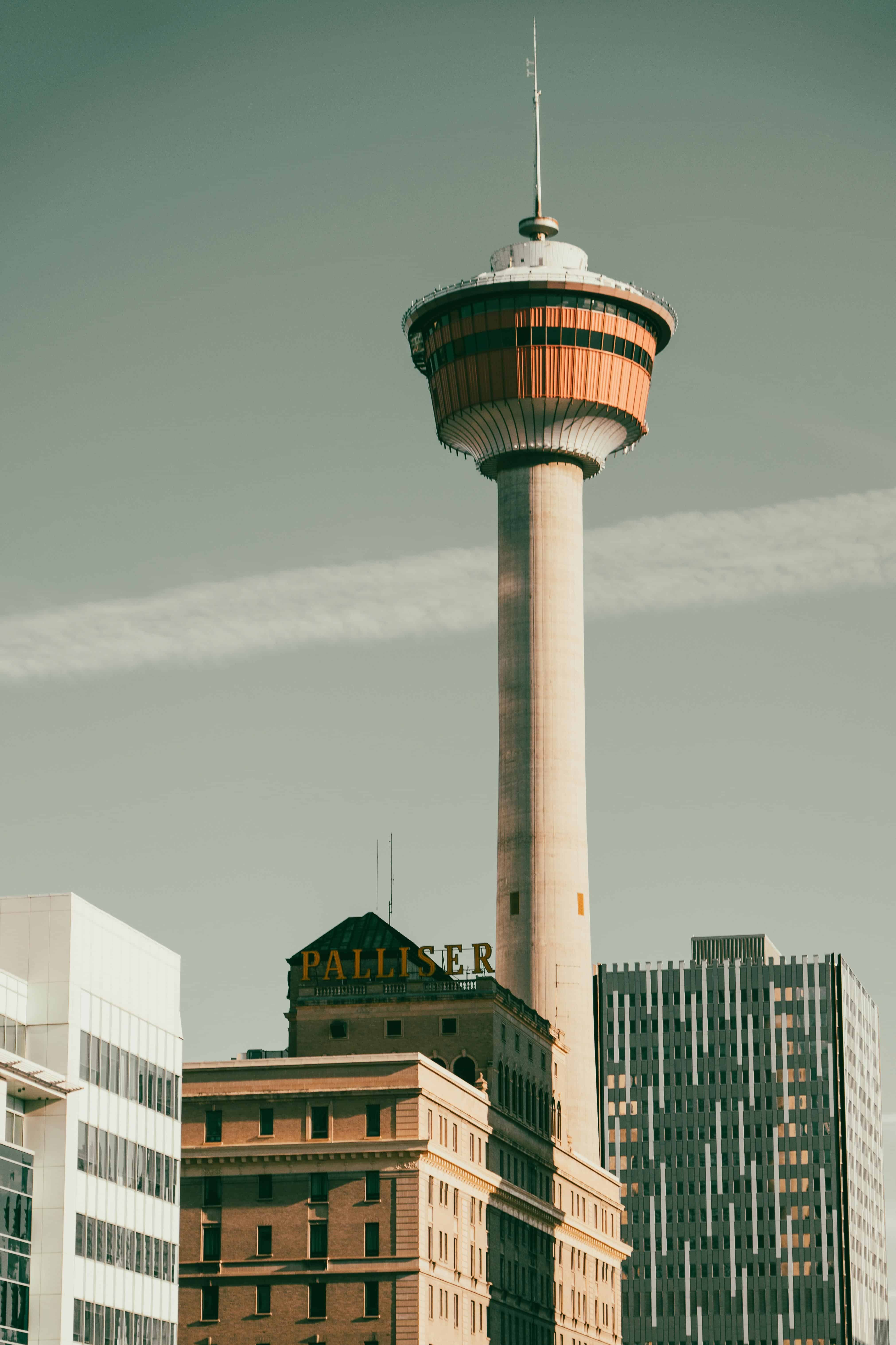 Calgary Tower above city buildings, clear sky background.