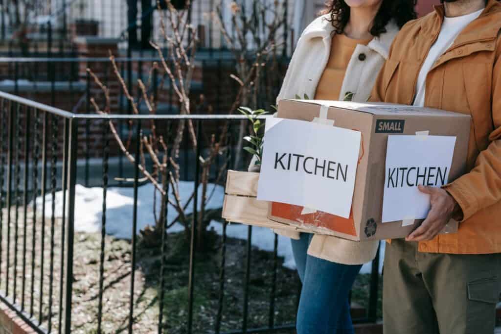 Couple carrying kitchen moving boxes outdoors