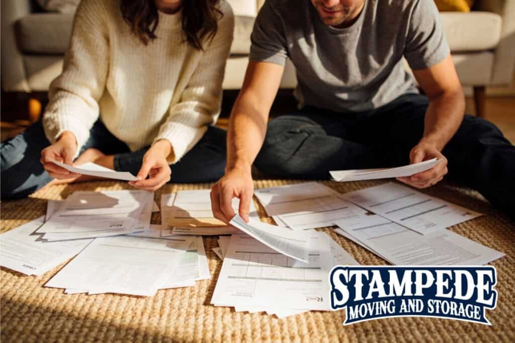 Couple organizing documents on the floor, Stampede logo visible.