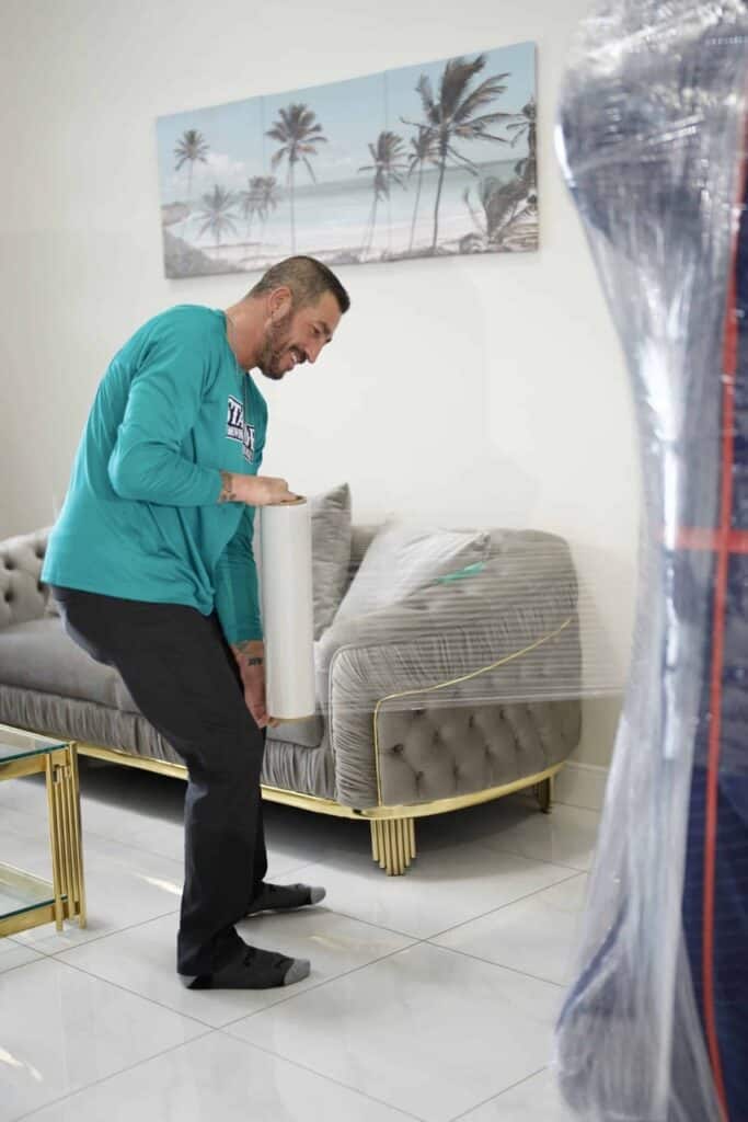 Person wrapping a sofa with plastic film
