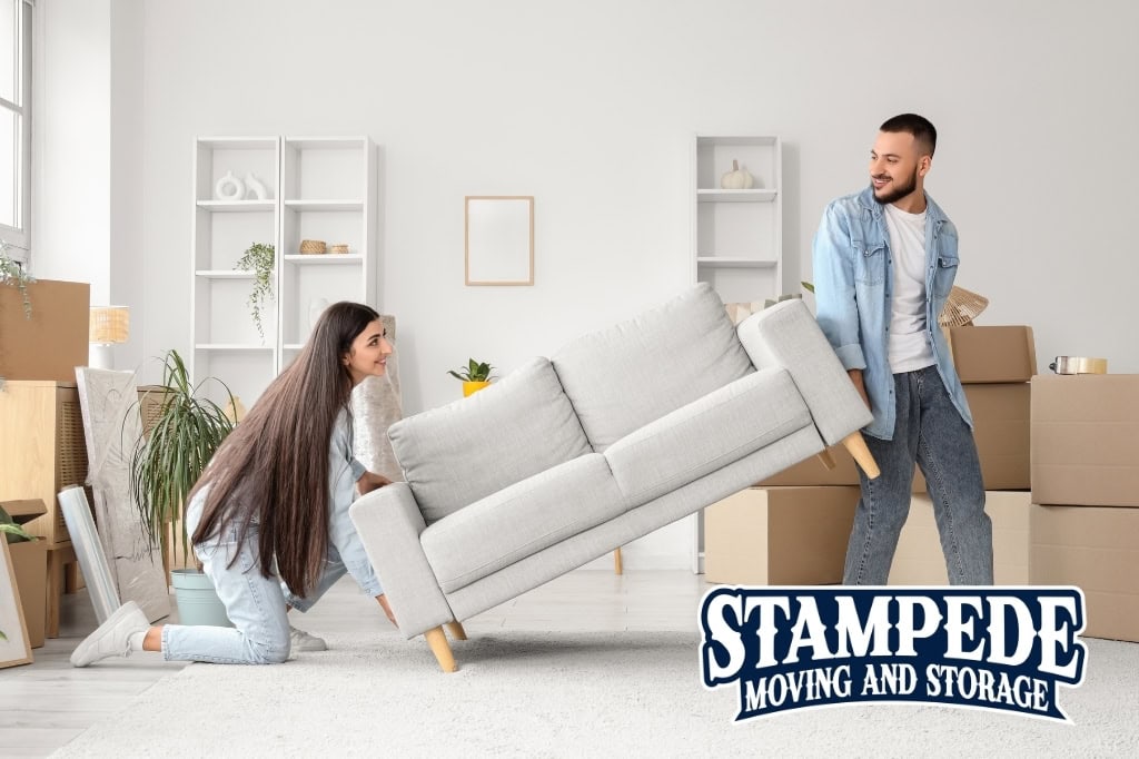 Couple moving sofa in living room with boxes.