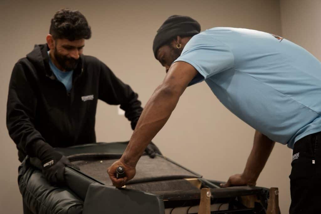 Two men repairing a piece of furniture