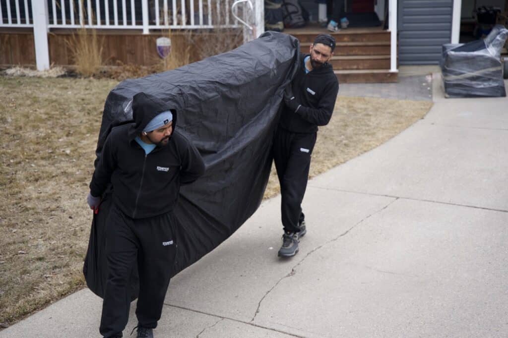 Two movers carrying a large covered item