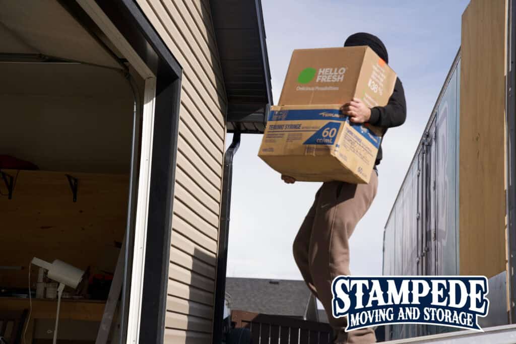 Person carrying a moving box outside.