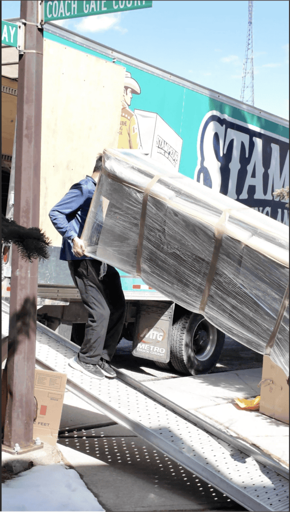 Mover carrying wrapped furniture down truck ramp