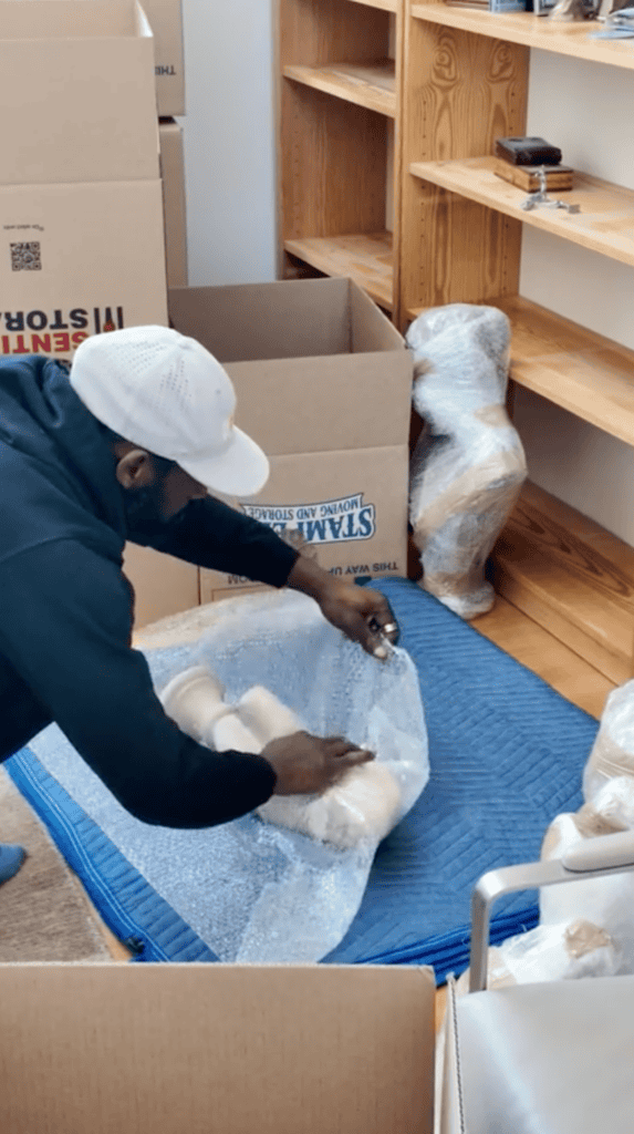 professional mover carefully wraps a fragile decorative item with bubble wrap to protect it during packing and transport